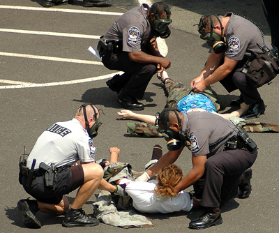 In a parking lot, police officers tend to civilians who are lying on the ground.  