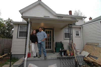 A woman and man stand together in front of a house.