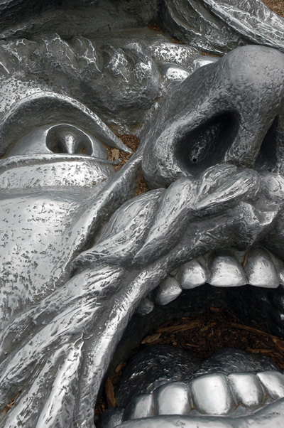 A bronze sculpture of a man's face. The mouth is open and the eyes look terrified.