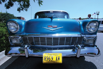 An antique car is blue and has a lot of chrome.  The license plate says "Virginia 8969 AW Antique." 
