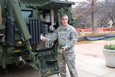 A man in a military uniform stands in front of a combat vehicle.