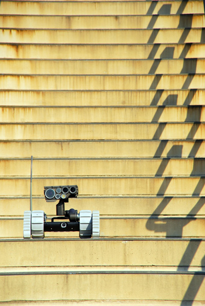 A small tracked robot sits on a stone staircase.