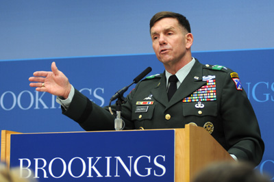 A man in a military uniform stands behind a lectern. The word "Brookings" appears on both the lectern and on the wall behind him.