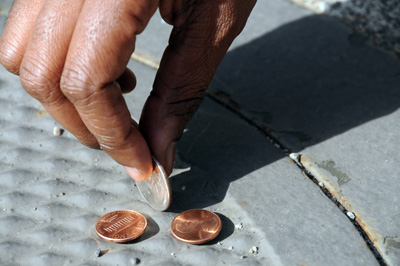 A hand picks up change off the ground.