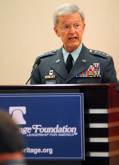 A man in a military uniform stands behind a lectern.  The lectern has a sign that says "Heritage Foundation Leadership for America."