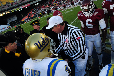 Football players on a field gather around a referee. 