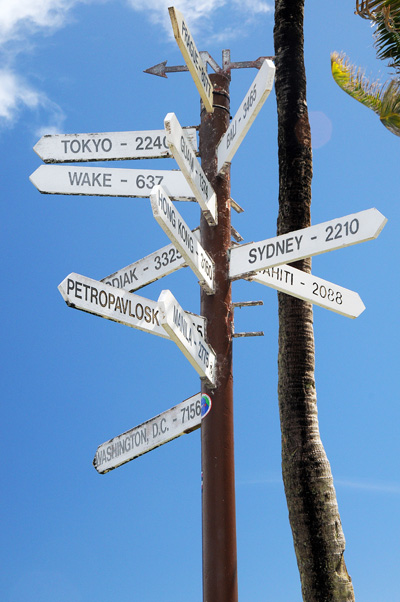 A sign post shows the distance of various cities, including Washington DC at 7,156 miles; Sydney at 2,210 miles; Wake Island at 637 miles; and Tokyo at 2240 miles.