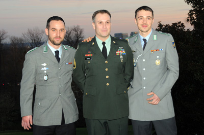 Two men in German military uniforms flank a man in an American military uniform.