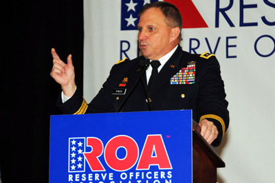 A man in a military uniform stands behind a lectern. A sign on the lectern reads "ROA Reserve Officers Association."  