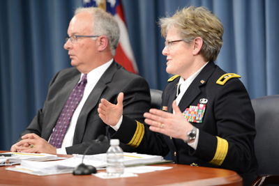 A woman in a military uniform and a man in a suit sit together at a table.