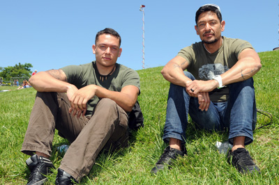 Two men sit on a grassy hill.