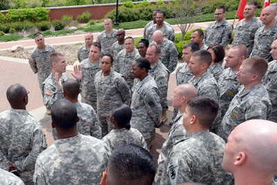 Dozens of individuals in military uniforms stand around a man in a military uniform.