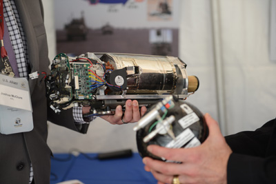 A hand holds what appears to be a motor with attached electronics.  Another hand appears to hold a similar device.