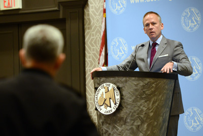 A man in a suit stands behind a lectern.  The lectern has a logo which reads "Association of the United States Army." 