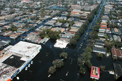 Seen from high above, the streets of a city are flooded.  Buildings are surrounded with water. 