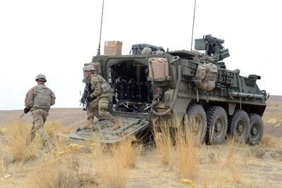 Soldiers exit the rear of a combat vehicle.