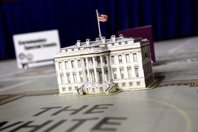 A tiny model of the White House sits atop a huge map. The words "The White House" appear on the map in front of the model.