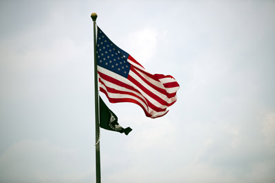 A small POW/MIA flag flies from a flagpole beneath an American flag.