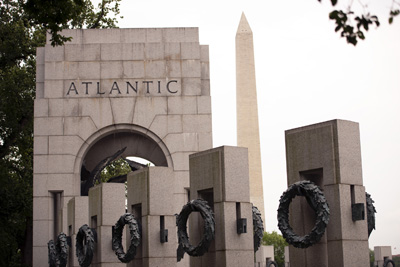 A large stone arch bears the word "Atlantic." Metal wreaths hang from other stone monuments. In the background is the Washington Monument.