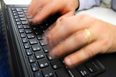 Fingers type on a keyboard.