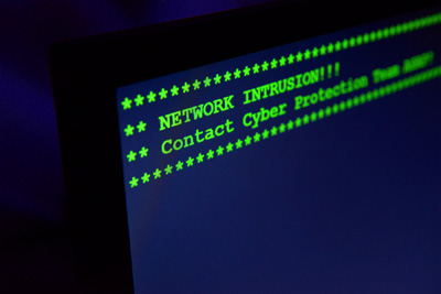 A computer screen reads "Network Intrusion!! Contact Cyber Protection Team ASAP!"